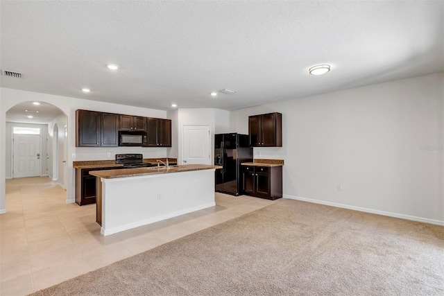 kitchen featuring light colored carpet, black appliances, an island with sink, and a textured ceiling