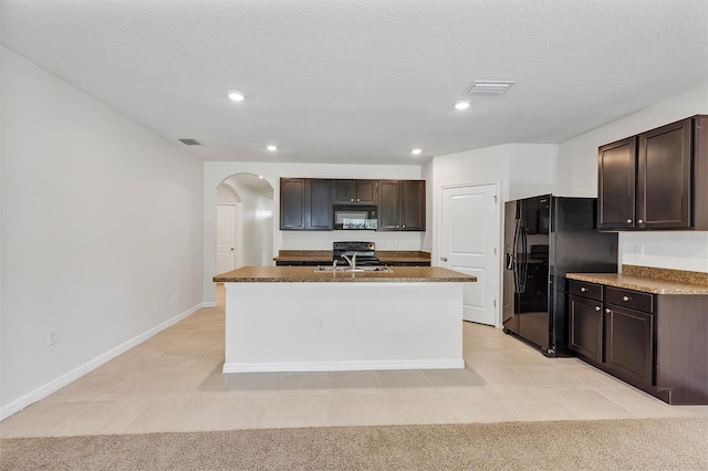 kitchen with an island with sink, light colored carpet, dark brown cabinetry, black appliances, and a textured ceiling