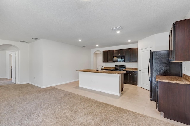 kitchen with light colored carpet, an island with sink, a textured ceiling, and black appliances