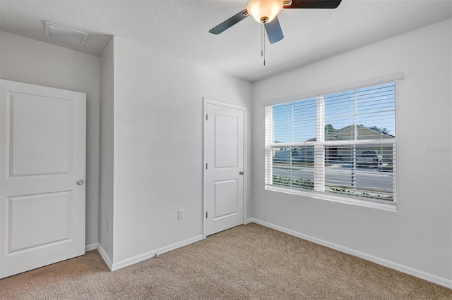 carpeted spare room with ceiling fan and a textured ceiling