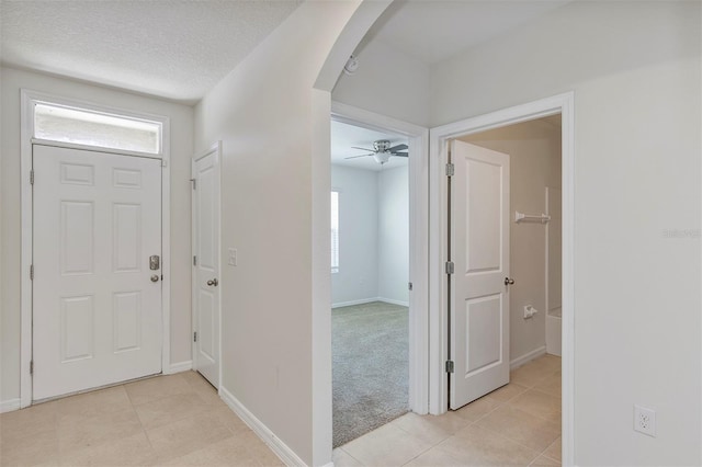 foyer with ceiling fan, a wealth of natural light, a textured ceiling, and light tile patterned flooring