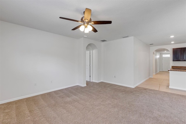 spare room featuring ceiling fan, light colored carpet, and a textured ceiling