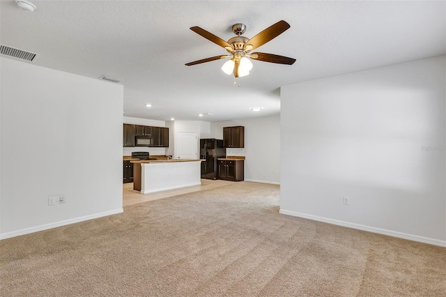 unfurnished living room with a textured ceiling, light colored carpet, and ceiling fan