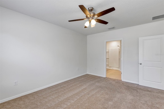 unfurnished bedroom with light carpet, ceiling fan, ensuite bath, and a textured ceiling