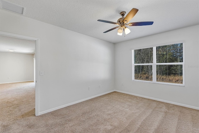 unfurnished room featuring ceiling fan, light colored carpet, and a textured ceiling