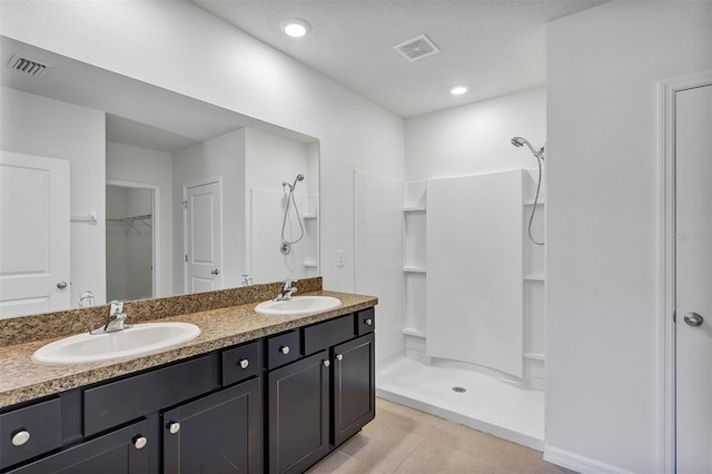 bathroom with vanity, tile patterned flooring, a textured ceiling, and a shower