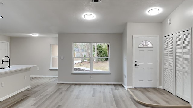 foyer entrance with sink, light hardwood / wood-style floors, and a textured ceiling