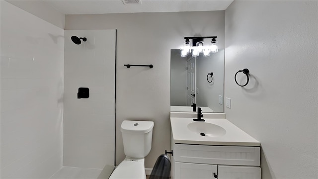 bathroom with vanity, toilet, and a tile shower