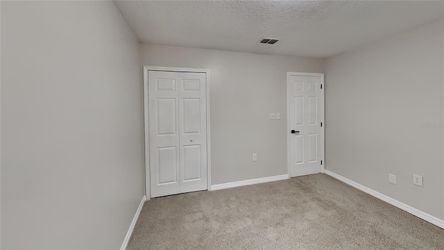 unfurnished bedroom featuring light colored carpet, a closet, and a textured ceiling