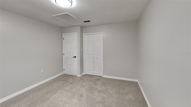 unfurnished bedroom featuring light colored carpet, a textured ceiling, and a closet