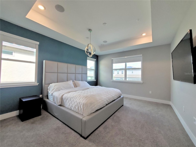 bedroom featuring light carpet and a tray ceiling