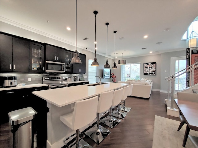 kitchen featuring a breakfast bar, sink, an island with sink, pendant lighting, and stainless steel appliances