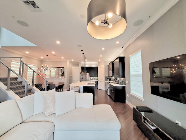 living room with crown molding, dark wood-type flooring, and an inviting chandelier