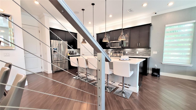 kitchen with a kitchen breakfast bar, stainless steel appliances, pendant lighting, backsplash, and a kitchen island