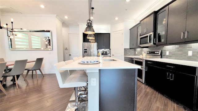 kitchen featuring sink, pendant lighting, a kitchen breakfast bar, stainless steel appliances, and a kitchen island with sink