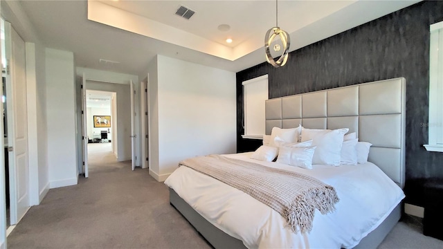 bedroom with a tray ceiling and light colored carpet