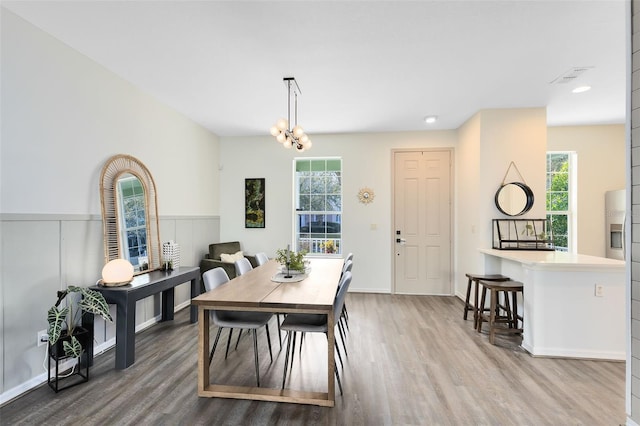 dining area with hardwood / wood-style flooring and an inviting chandelier