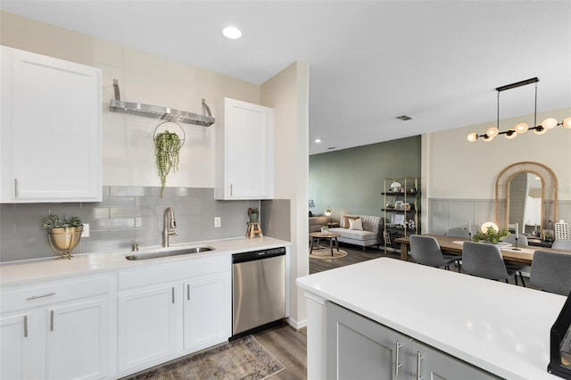 kitchen with white cabinetry, sink, hanging light fixtures, stainless steel dishwasher, and dark wood-type flooring