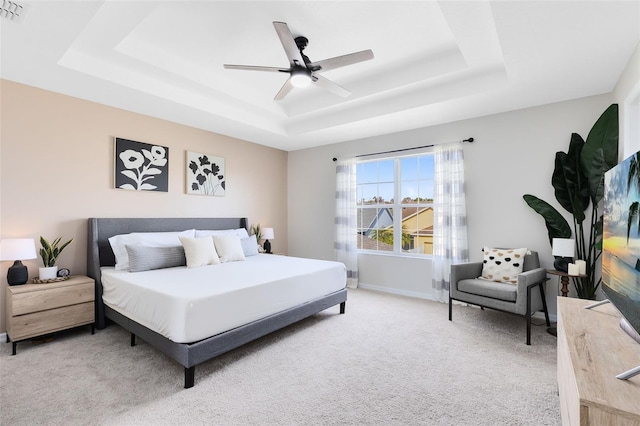 carpeted bedroom with a raised ceiling and ceiling fan