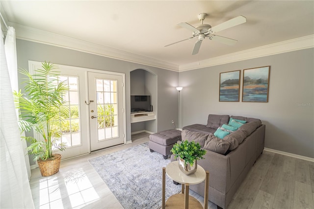 living room with ornamental molding, light hardwood / wood-style flooring, ceiling fan, and french doors