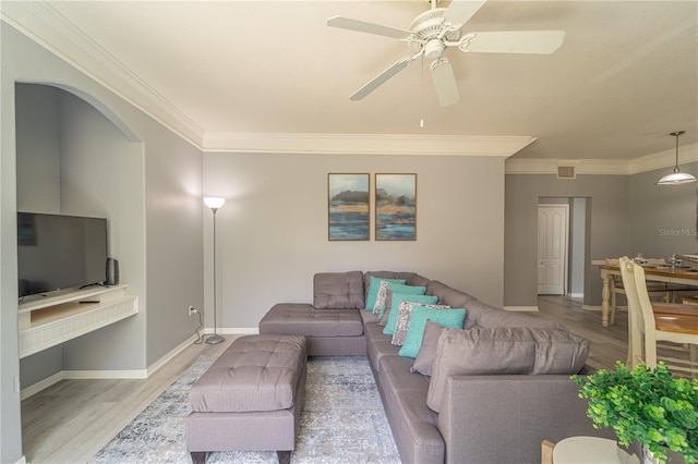 living room featuring wood-type flooring, ornamental molding, and ceiling fan