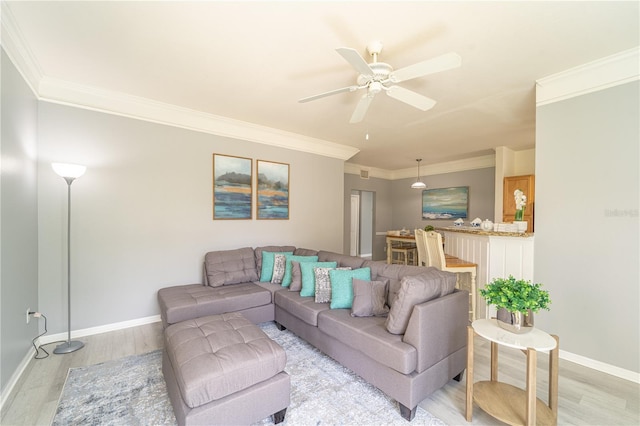 living room with ceiling fan, ornamental molding, and light wood-type flooring