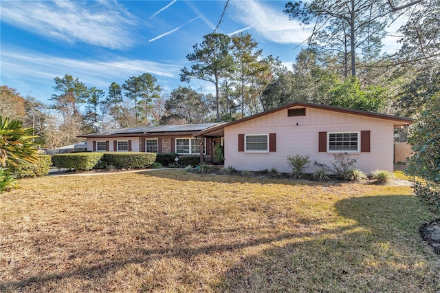 single story home featuring a front lawn and solar panels