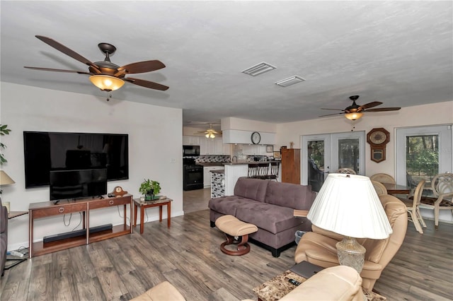 living room featuring french doors, ceiling fan, hardwood / wood-style floors, and a textured ceiling