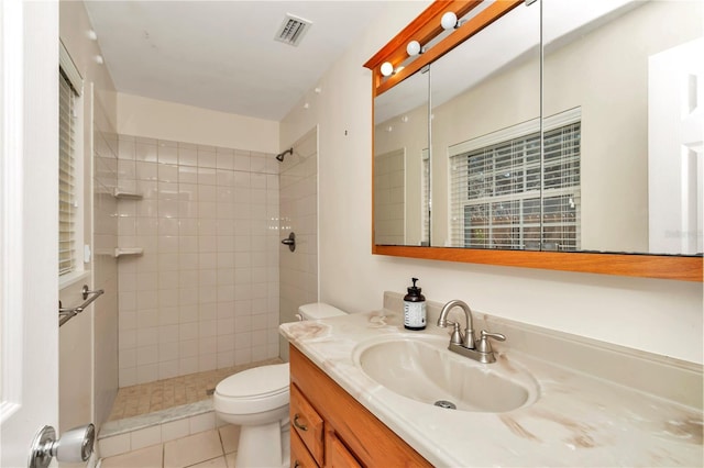 bathroom featuring tile patterned flooring, vanity, tiled shower, and toilet