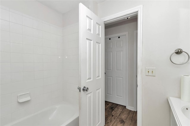 bathroom with hardwood / wood-style flooring, vanity, and tiled shower / bath combo