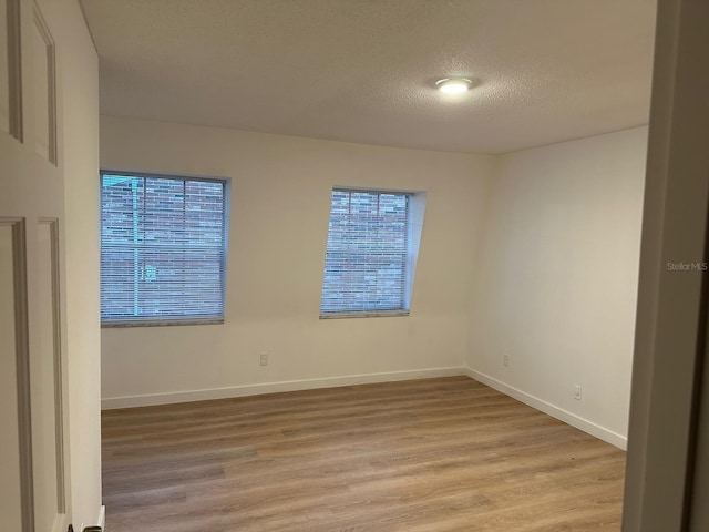 spare room featuring a textured ceiling and light wood-type flooring