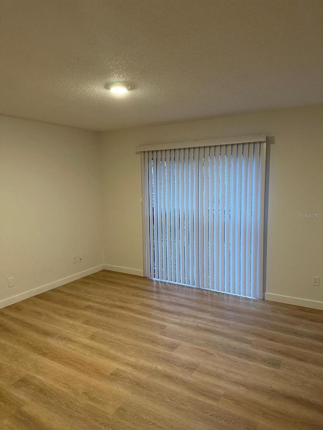 spare room with light hardwood / wood-style flooring and a textured ceiling