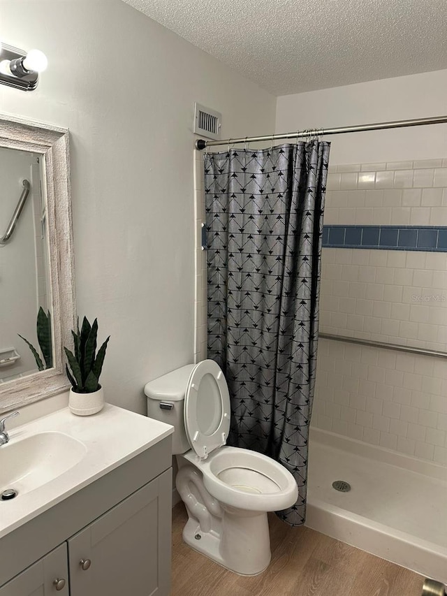 bathroom featuring vanity, wood-type flooring, a textured ceiling, a shower with curtain, and toilet