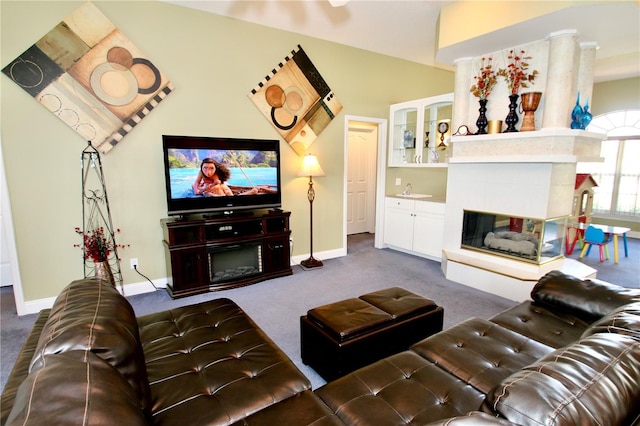 living room with a tiled fireplace and dark colored carpet