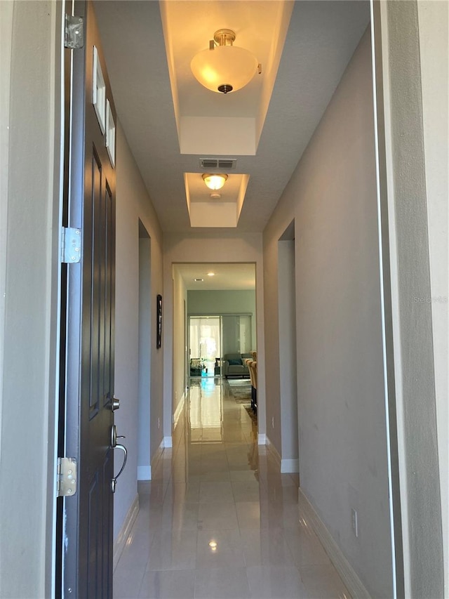 corridor featuring a raised ceiling and tile patterned flooring