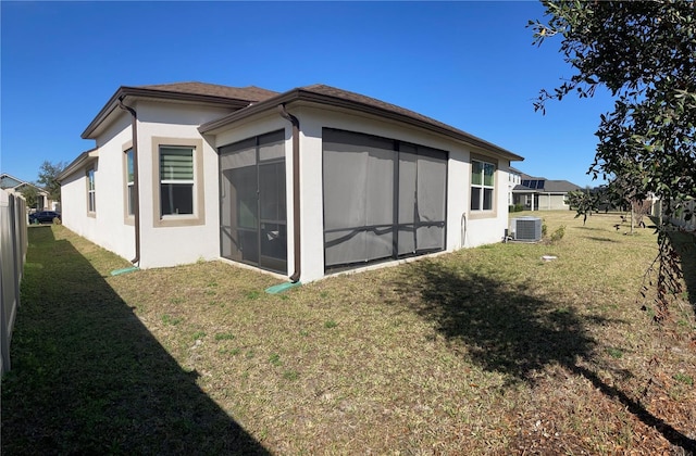 rear view of house featuring a sunroom, a yard, and central AC