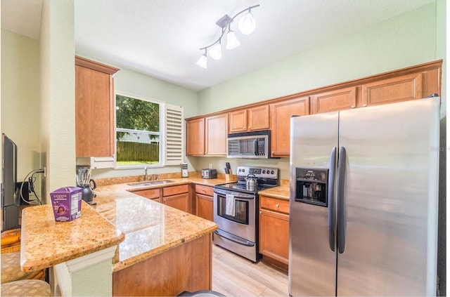 kitchen featuring appliances with stainless steel finishes, sink, a breakfast bar area, light stone counters, and kitchen peninsula