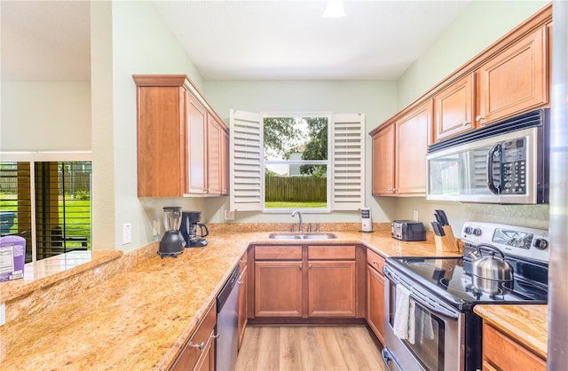 kitchen with light stone counters, sink, light hardwood / wood-style flooring, and stainless steel appliances