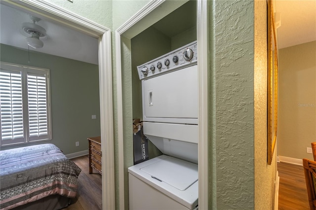 laundry area with stacked washer and dryer and wood-type flooring