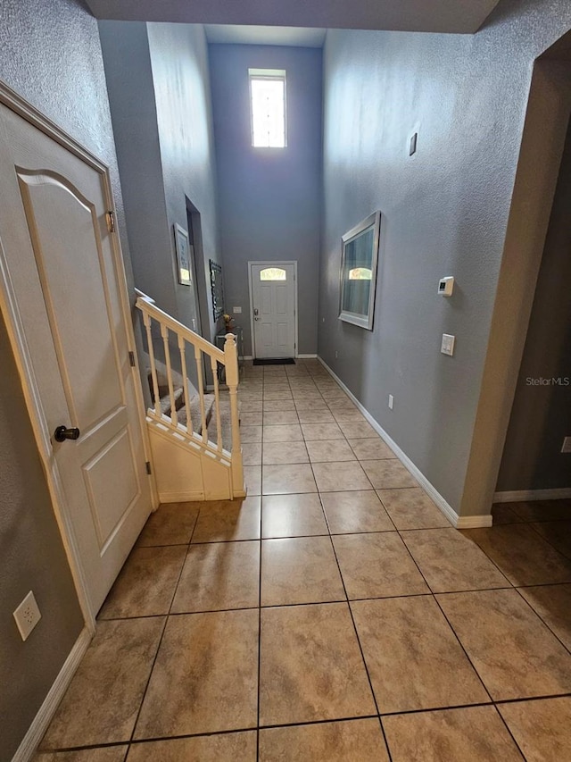 doorway to outside with a high ceiling and light tile patterned flooring