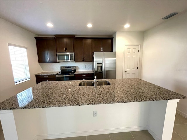 kitchen with stainless steel appliances, tile patterned flooring, and a center island with sink