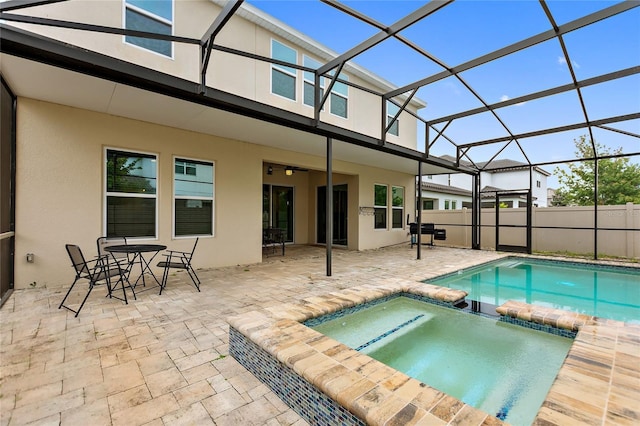 rear view of house featuring a swimming pool with hot tub, a patio area, and glass enclosure