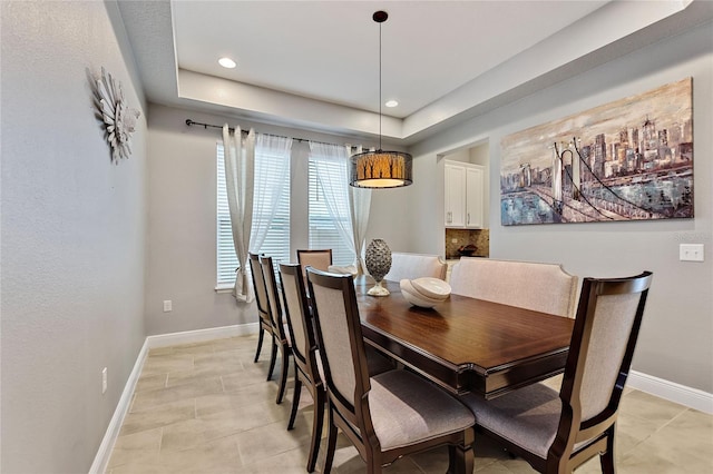 dining room featuring light tile patterned floors and a tray ceiling