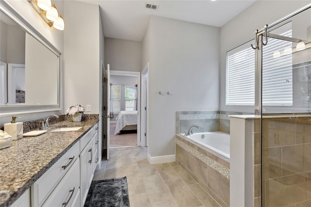 bathroom with vanity, tile patterned flooring, and a relaxing tiled tub