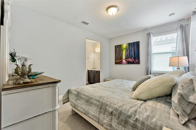 carpeted bedroom with a textured ceiling and ensuite bathroom