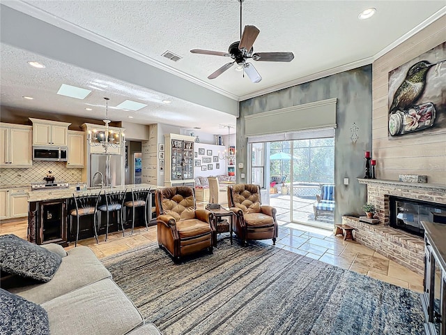 living room featuring sink, crown molding, a brick fireplace, a textured ceiling, and ceiling fan