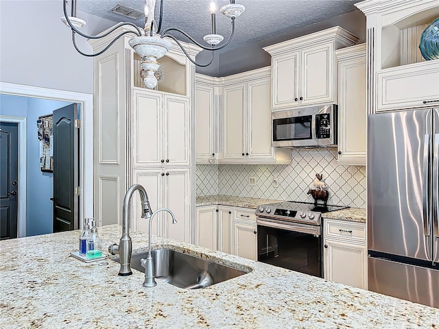 kitchen featuring decorative light fixtures, tasteful backsplash, sink, stainless steel appliances, and a textured ceiling