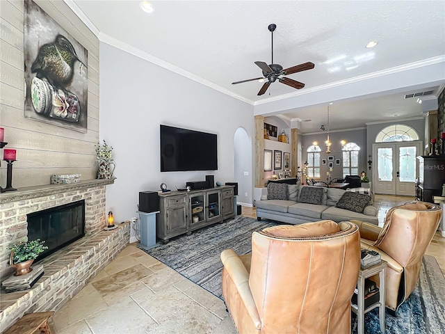 living room with a brick fireplace, ornamental molding, french doors, and ceiling fan