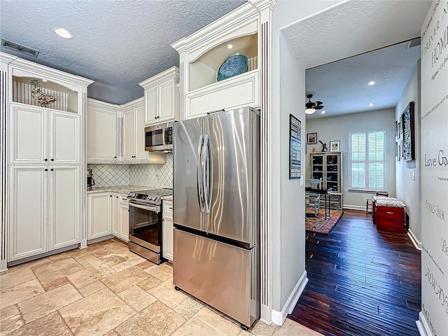 kitchen with white cabinetry, decorative backsplash, a textured ceiling, and appliances with stainless steel finishes