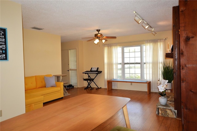 office featuring ceiling fan, wood-type flooring, rail lighting, and a textured ceiling